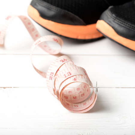 running shoes and measuring tape on white wood tableの写真素材