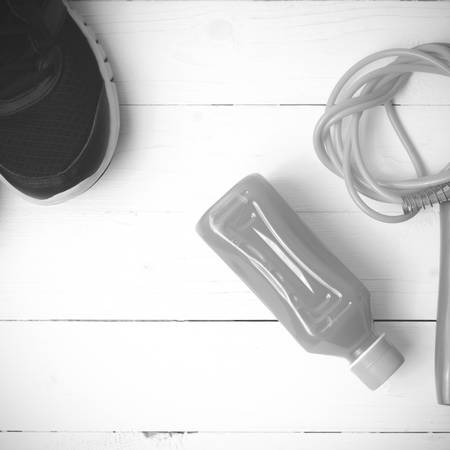 fitness equipment : running shoes,jumping rope and orange juice on white wood background black and white tone color styleの写真素材