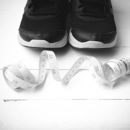 running shoes and measuring tape on white wood table black and white tone color styleの写真素材