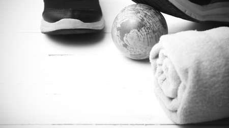 running shoes,towel and earth ball on white wood table concept world healthy black and white tone color styleの写真素材