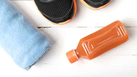 running shoes,towel and orange juice on white wood tableの写真素材