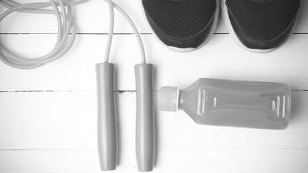 fitness equipment : running shoes,jumping rope and orange juice on white wood background black and...