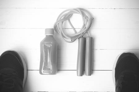 fitness equipment : running shoes,jumping rope and orange juice on white wood background black and white tone color styleの写真素材