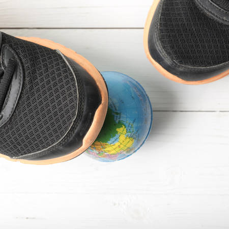 running shoes and earth ball on white wood table concept world healthyの写真素材