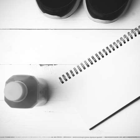 running shoes,orange juice and notepad on white wood background black and white tone color styleの写真素材