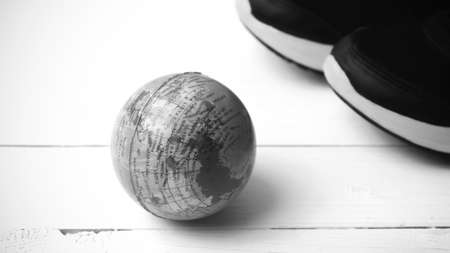 running shoes and earth ball on white wood table concept world healthy black and white tone color styleの写真素材