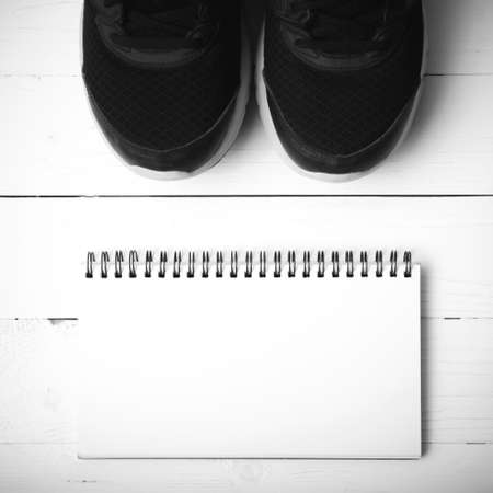 running shoes and notepad on white wood table black and white tone color styleの写真素材