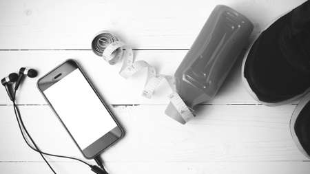 running shoes,orange juice,measuring tape and phone on white wood background black and white tone color styleの写真素材