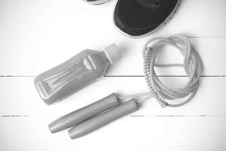 fitness equipment : running shoes,jumping rope and orange juice on white wood background black and...