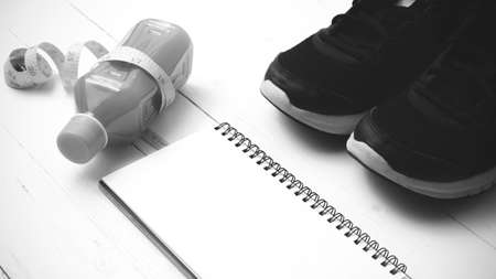 running shoes,orange juice,measuring tape and notepad on white wood background black and white tone color styleの写真素材
