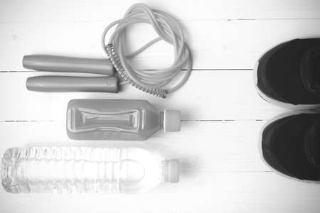 fitness equipment : running shoes,jumping rope,drinking water and orange juice on white wood background black and white tone color styleの写真素材