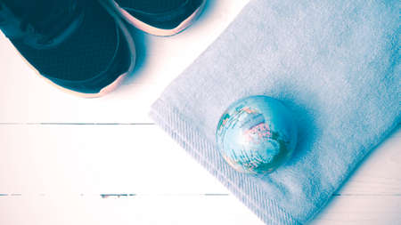 running shoes,towel and earth ball on white wood table concept world healthy vintage styleの写真素材