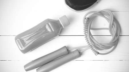 fitness equipment : running shoes,jumping rope and orange juice on white wood background black and white tone color styleの写真素材