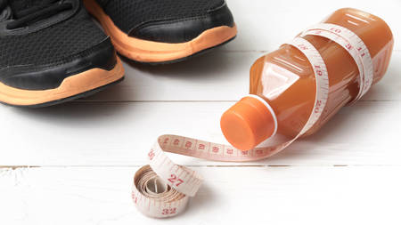 running shoes,orange juice and measuring tape on white wood backgroundの写真素材