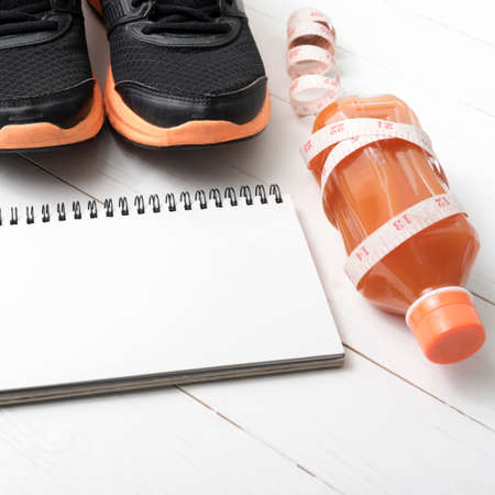 running shoes,orange juice,measuring tape and notepad on white wood backgroundの写真素材