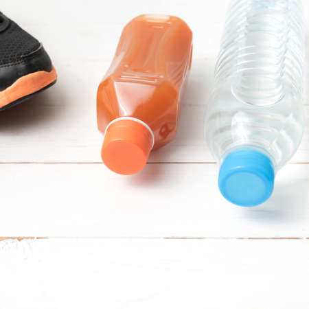running shoes,drinking water and orange juice on white wood tableの写真素材