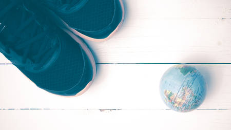 running shoes and earth ball on white wood table concept world healthy vintage styleの写真素材