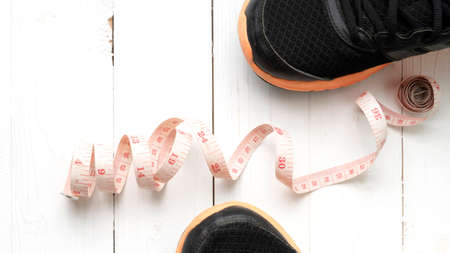 running shoes and measuring tape on white wood tableの写真素材