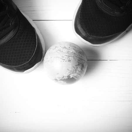 running shoes and earth ball on white wood table concept world healthy black and white tone color styleの写真素材