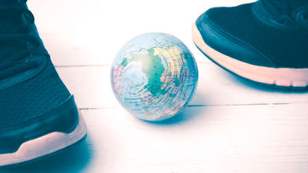 running shoes and earth ball on white wood table concept world healthy vintage styleの写真素材