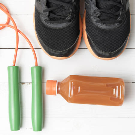 fitness equipment : running shoes,jumping rope and orange juice on white wood backgroundの写真素材