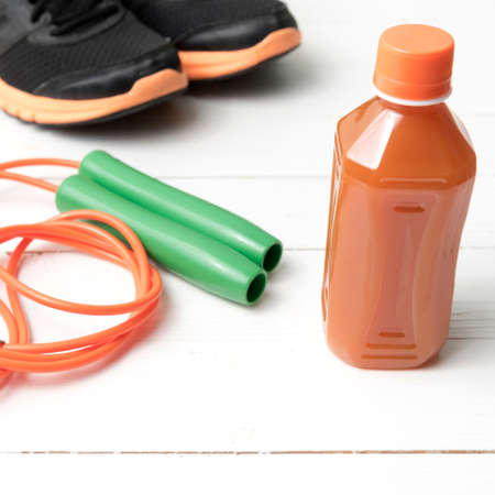 fitness equipment : running shoes,jumping rope and orange juice on white wood backgroundの写真素材