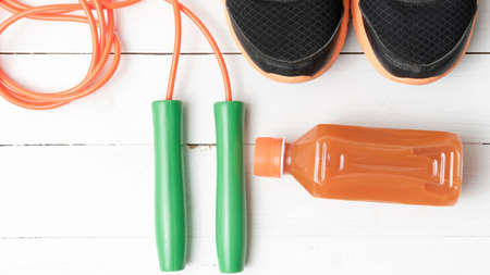 fitness equipment : running shoes,jumping rope and orange juice on white wood backgroundの写真素材