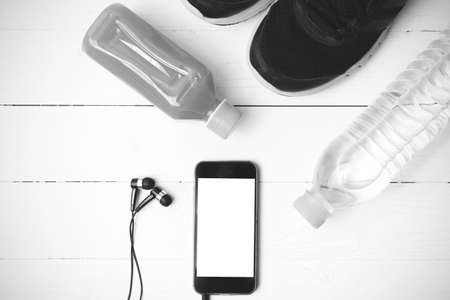 running shoes,orange juice,drinking water and phone on white wood background black and white tone color styleの写真素材