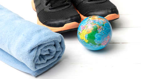 running shoes,towel and earth ball on white wood table concept world healthyの写真素材