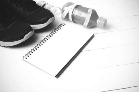 running shoes,orange juice,measuring tape and notepad on white wood background black and white tone color styleの写真素材