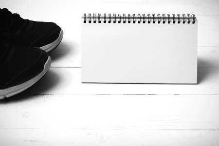 running shoes and notepad on white wood table black and white tone color styleの写真素材