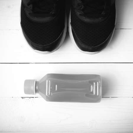 running shoes and orange juice on white wood table black and white tone color styleの写真素材