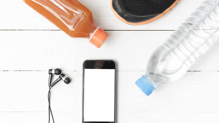 running shoes,orange juice,drinking water and phone on white wood backgroundの写真素材