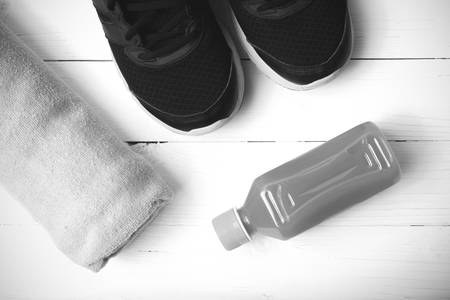 running shoes,towel and orange juice on white wood table black and white tone color styleの写真素材