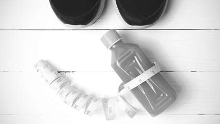 running shoes,orange juice and measuring tape on white wood background black and white tone color styleの写真素材