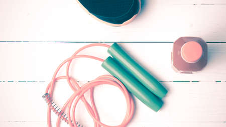 fitness equipment : running shoes,jumping rope and orange juice on white wood background vintage tone styleの写真素材