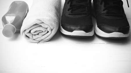 running shoes,towel and orange juice on white wood table black and white tone color styleの写真素材