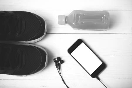 running shoes,orange juice and phone on white wood background black and white tone color styleの写真素材