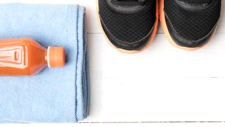 running shoes,towel and orange juice on white wood tableの写真素材