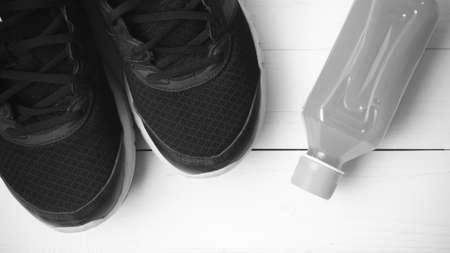 running shoes and orange juice on white wood table black and white tone color style