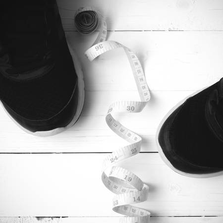 running shoes and measuring tape on white wood table black and white tone color styleの写真素材
