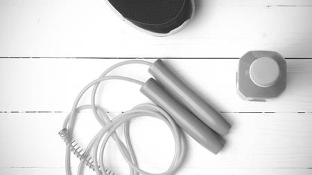fitness equipment : running shoes,jumping rope and orange juice on white wood background black and white tone color styleの写真素材