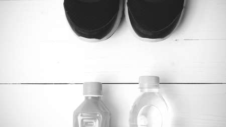 running shoes,drinking water and orange juice on white wood table black and white tone color styleの写真素材