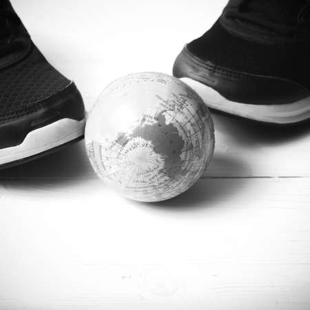 running shoes and earth ball on white wood table concept world healthy black and white tone color styleの写真素材