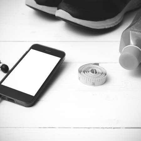 running shoes,orange juice,measuring tape and phone on white wood background black and white tone color styleの写真素材