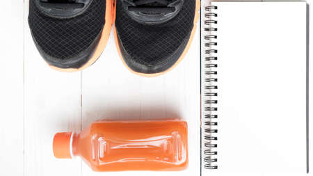 running shoes,orange juice and notepad on white wood backgroundの写真素材