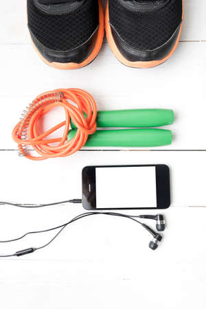 fitness equipment : running shoes,jumping rope and phone on white wood tableの写真素材