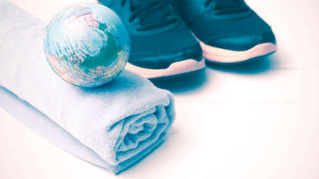 running shoes,towel and earth ball on white wood table concept world healthy vintage styleの写真素材