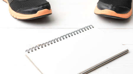running shoes and notepad on white wood table