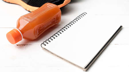 running shoes,orange juice and notepad on white wood backgroundの写真素材